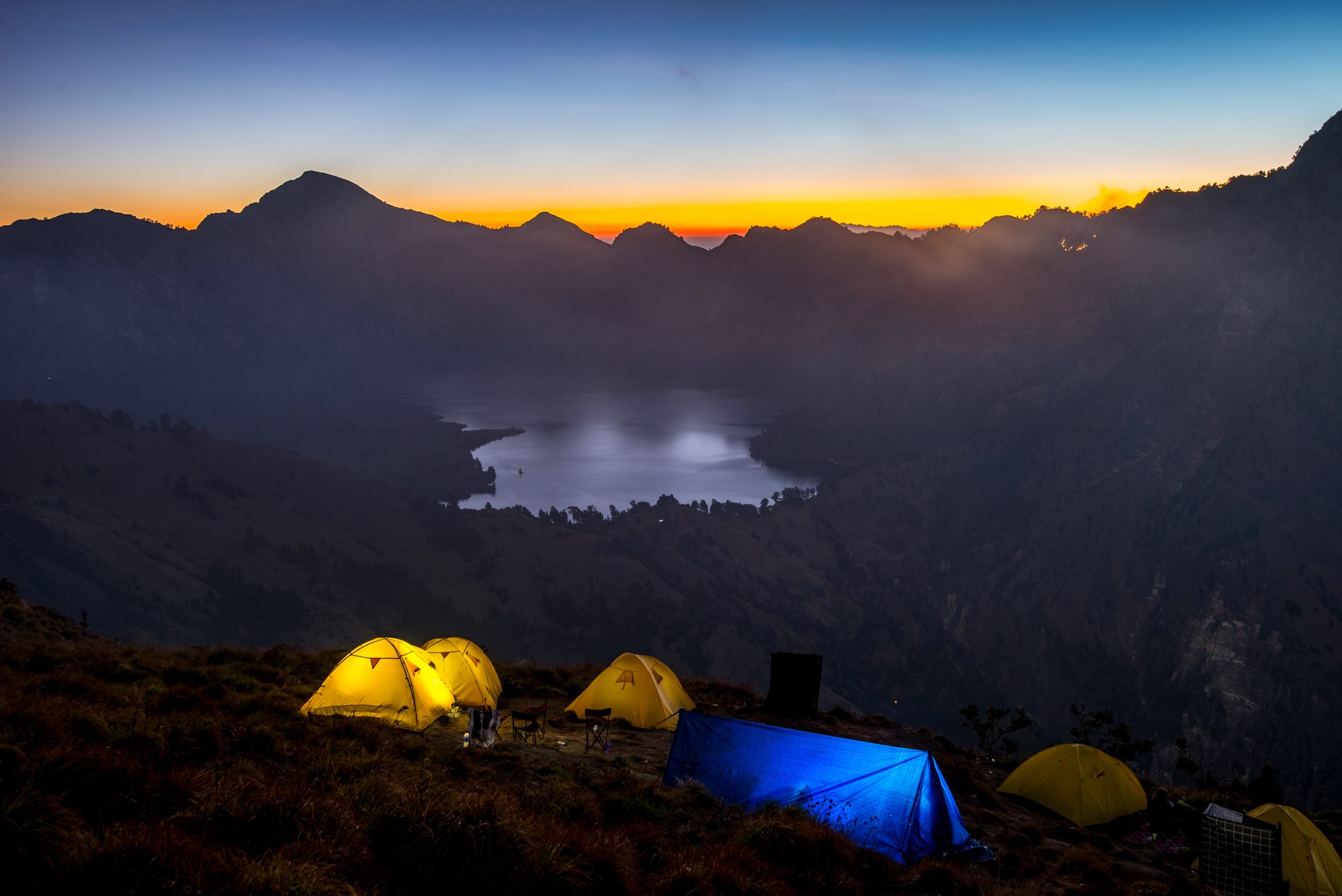 Mount Rinjani crater rim camp at sunset with glowing tents
