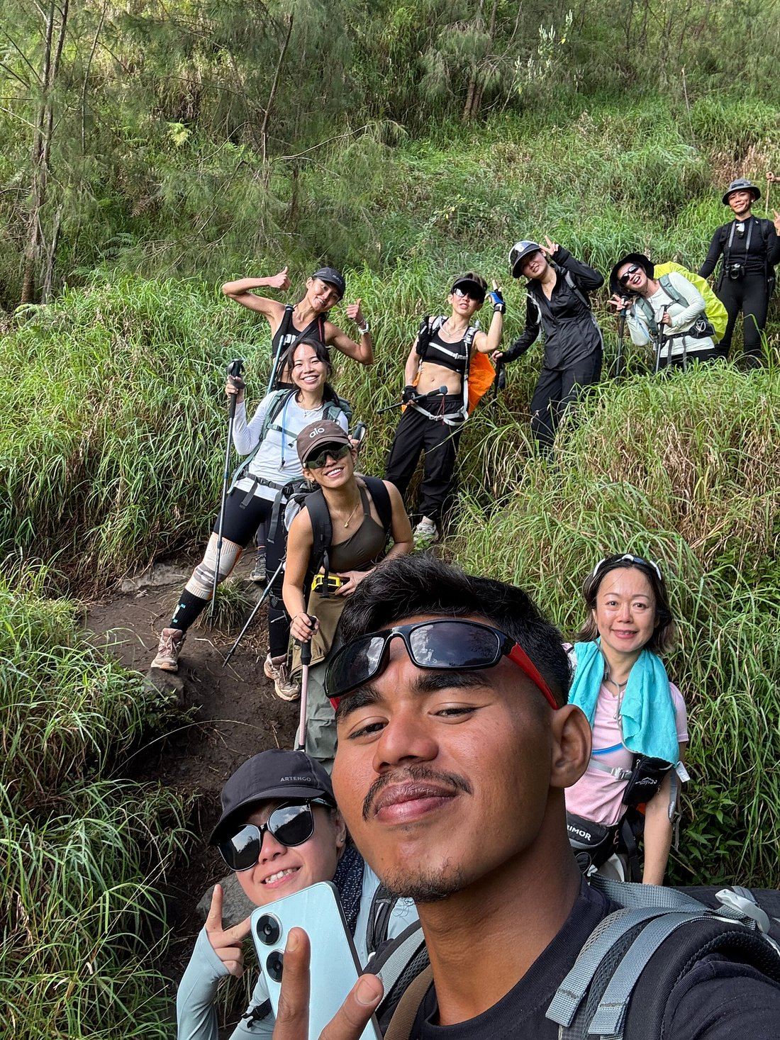 A shared trekking group taking a selfie with their guide on the Rinjani trail