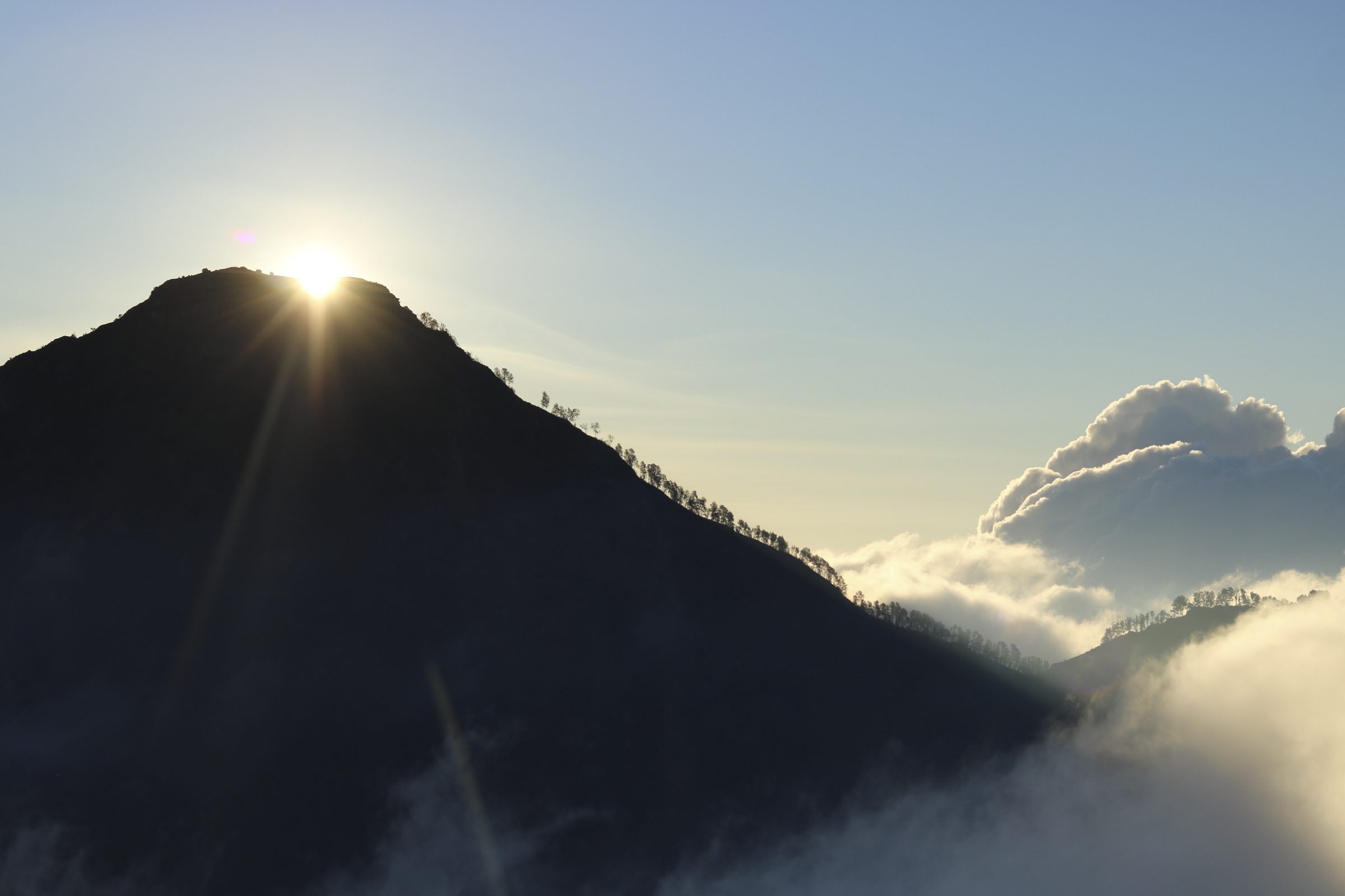 Sunrise breaking over the Mount Rinjani crater rim above a sea of clouds