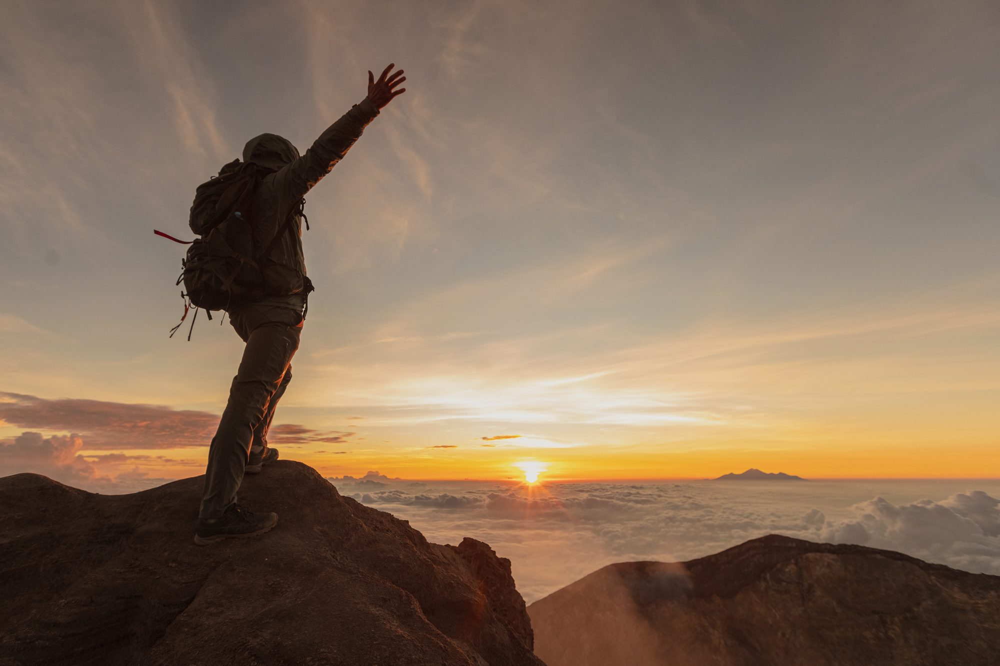 Trekker silhouette on the Rinjani summit at sunrise