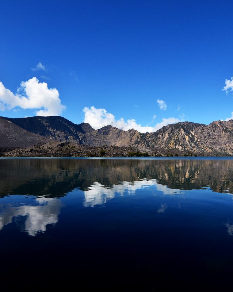 Segara Anak crater lake inside Mount Rinjani, turquoise water surrounded by volcanic walls