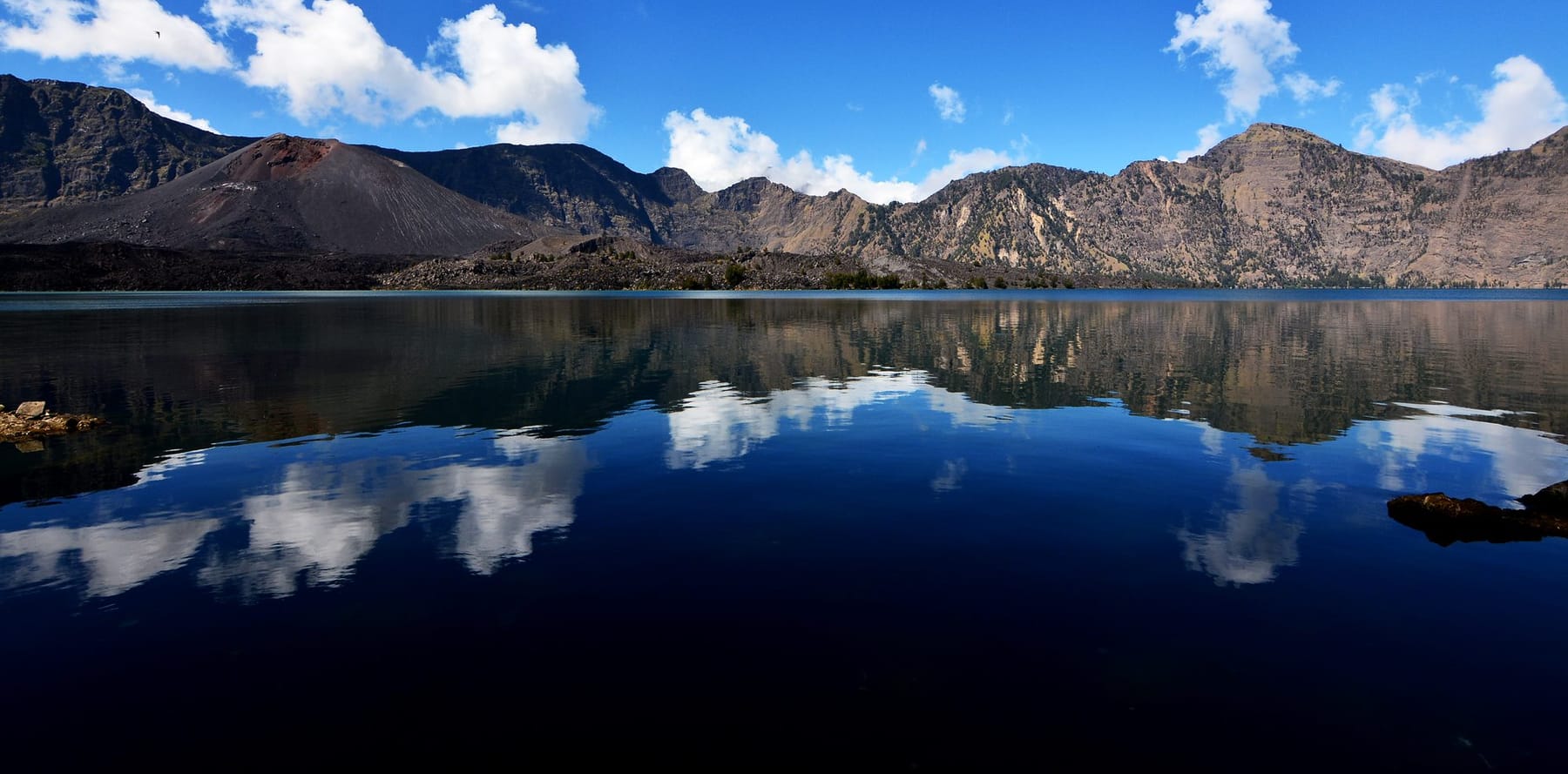 Segara Anak crater lake seen from the rim, with the summit cone reflected in the water